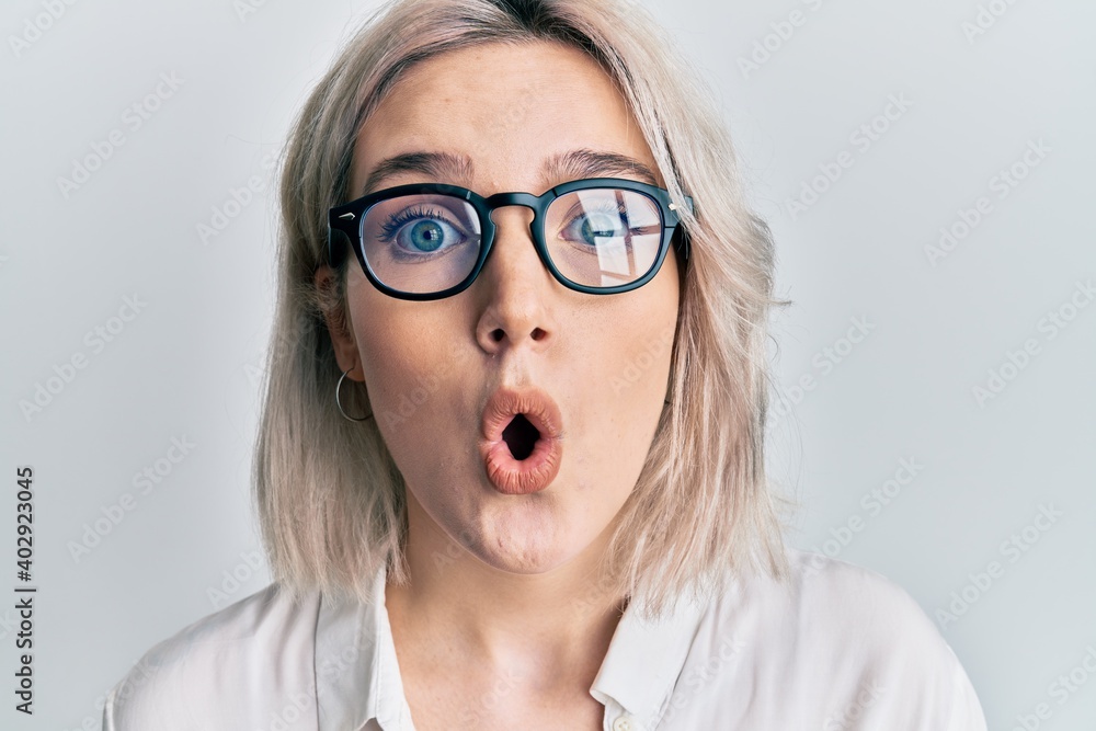 Young blonde girl wearing casual clothes and glasses scared and amazed with open mouth for surprise, disbelief face Young blonde girl wearing casual clothes and glasses scared and amazed with open mouth for surprise, disbelief face