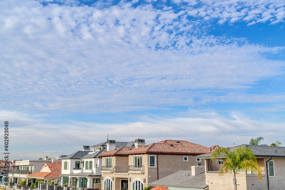 Blue sky and puffy clouds over houses in a prestigious seaside neighborhood