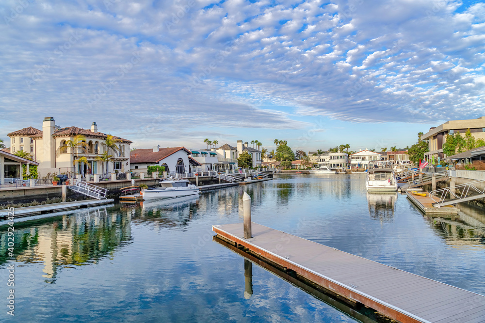 Boats and private docks on sea reflecting cloudy blue sky in Huntington Beach CA