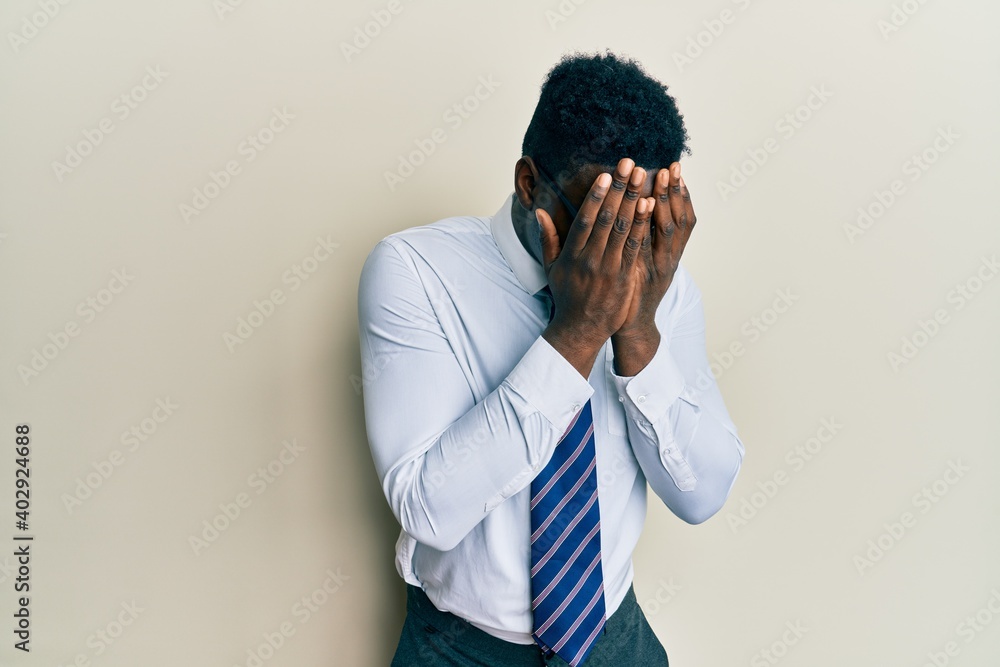 Handsome black man wearing glasses business shirt and tie with sad expression covering face with hands while crying. depression concept. Handsome black man wearing glasses business shirt and tie with sad expression covering face with hands while crying. depression concept.