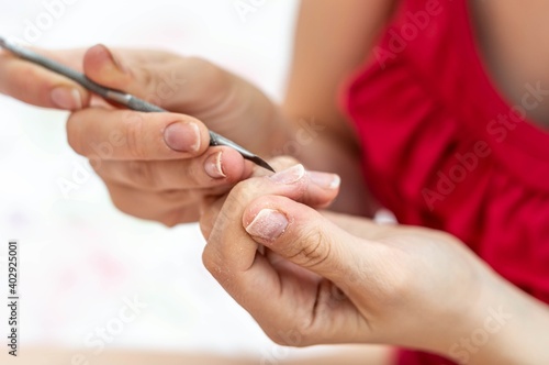 Woman's hands filing her nails with a red blouse.