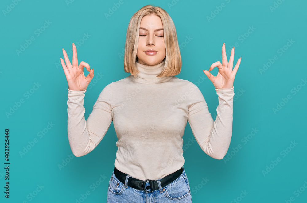 Young blonde woman wearing casual clothes relax and smiling with eyes closed doing meditation gesture with fingers. yoga concept. Young blonde woman wearing casual clothes relax and smiling with eyes closed doing meditation gesture with fingers. yoga concept.