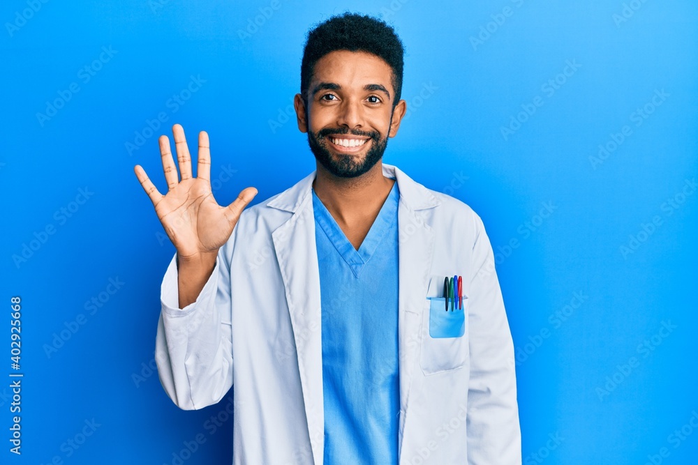 Handsome hispanic man with beard wearing doctor uniform showing and pointing up with fingers number five while smiling confident and happy. Handsome hispanic man with beard wearing doctor uniform showing and pointing up with fingers number five while smiling confident and happy.