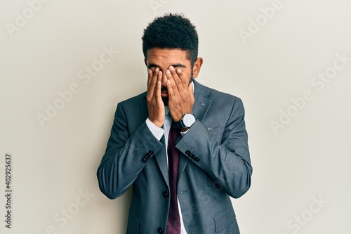 Handsome hispanic man with beard wearing business suit and tie rubbing eyes for fatigue and headache, sleepy and tired expression. vision problem