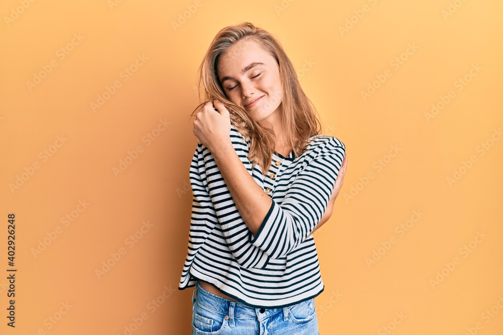 Beautiful blonde woman wearing casual clothes hugging oneself happy and positive, smiling confident. self love and self care Beautiful blonde woman wearing casual clothes hugging oneself happy and positive, smiling confident. self love and self care