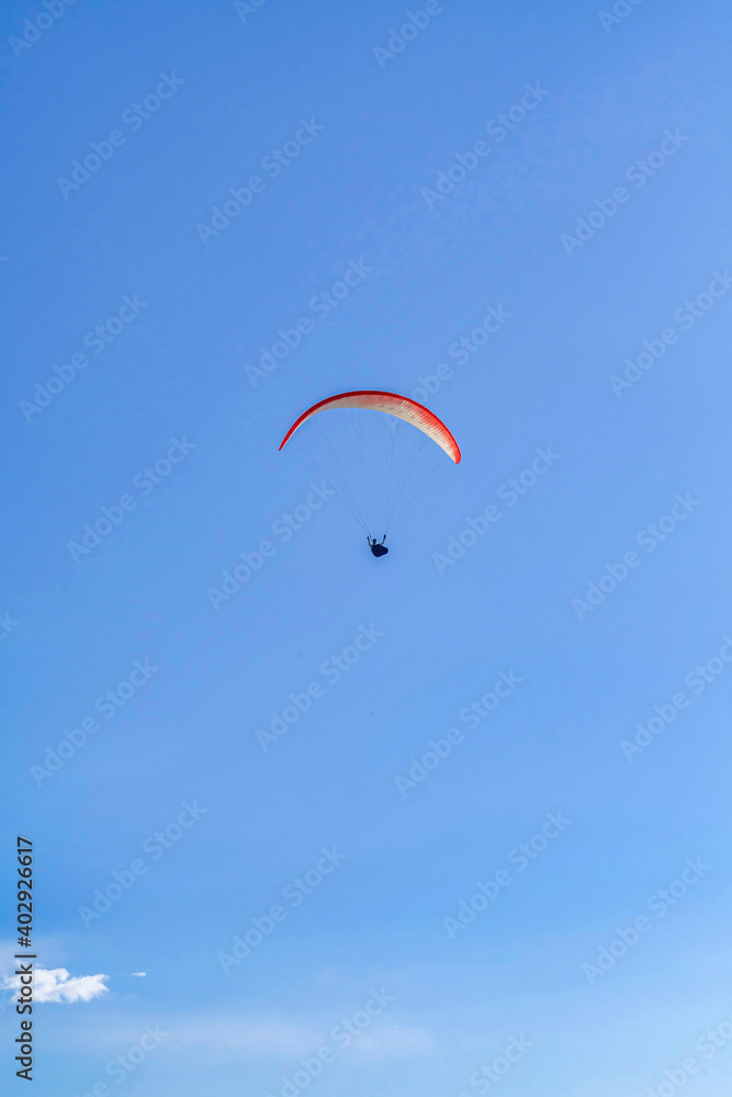 Parachuter with red parachute flying against blue sky in San Diego California Parachuter with red parachute flying against blue sky in San Diego California