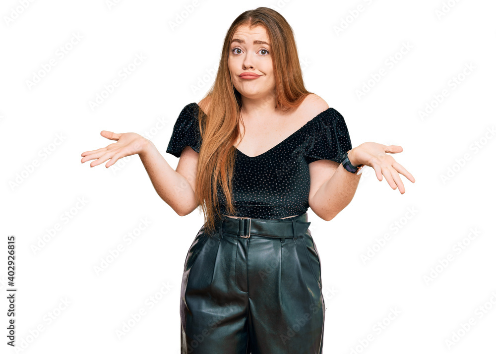Young beautiful redhead woman wearing elegant clothes clueless and confused expression with arms and hands raised. doubt concept. Young beautiful redhead woman wearing elegant clothes clueless and confused expression with arms and hands raised. doubt concept.