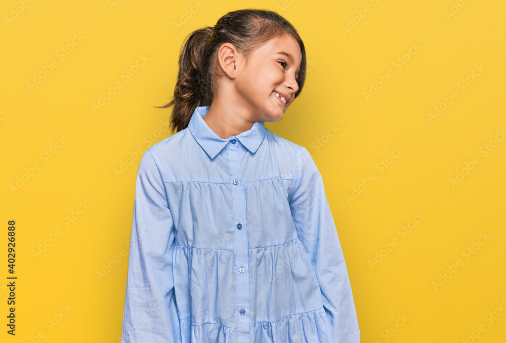 Little beautiful girl wearing casual clothes looking away to side with smile on face, natural expression. laughing confident.