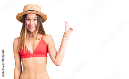 Beautiful brunette young woman wearing bikini showing and pointing up with fingers number two while smiling confident and happy.