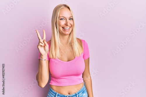 Young blonde girl wearing casual clothes showing and pointing up with fingers number two while smiling confident and happy. © Krakenimages.com