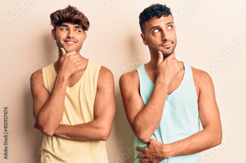Young gay couple wearing casual clothes with hand on chin thinking about question, pensive expression. smiling with thoughtful face. doubt concept. © Krakenimages.com