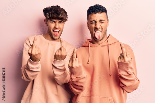 Young gay couple wearing casual clothes showing middle finger doing fuck you bad expression, provocation and rude attitude. screaming excited © Krakenimages.com