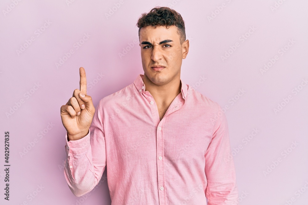 Hispanic young man pointing up with fingers clueless and confused expression. doubt concept. Hispanic young man pointing up with fingers clueless and confused expression. doubt concept.