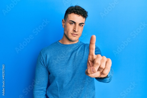 Hispanic young man wearing casual winter sweater pointing with finger up and angry expression, showing no gesture © Krakenimages.com
