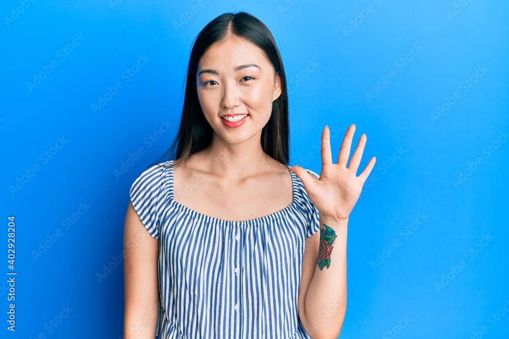 Young chinese woman wearing casual striped t-shirt showing and pointing up with fingers number five while smiling confident and happy. Young chinese woman wearing casual striped t-shirt showing and pointing up with fingers number five while smiling confident and happy.