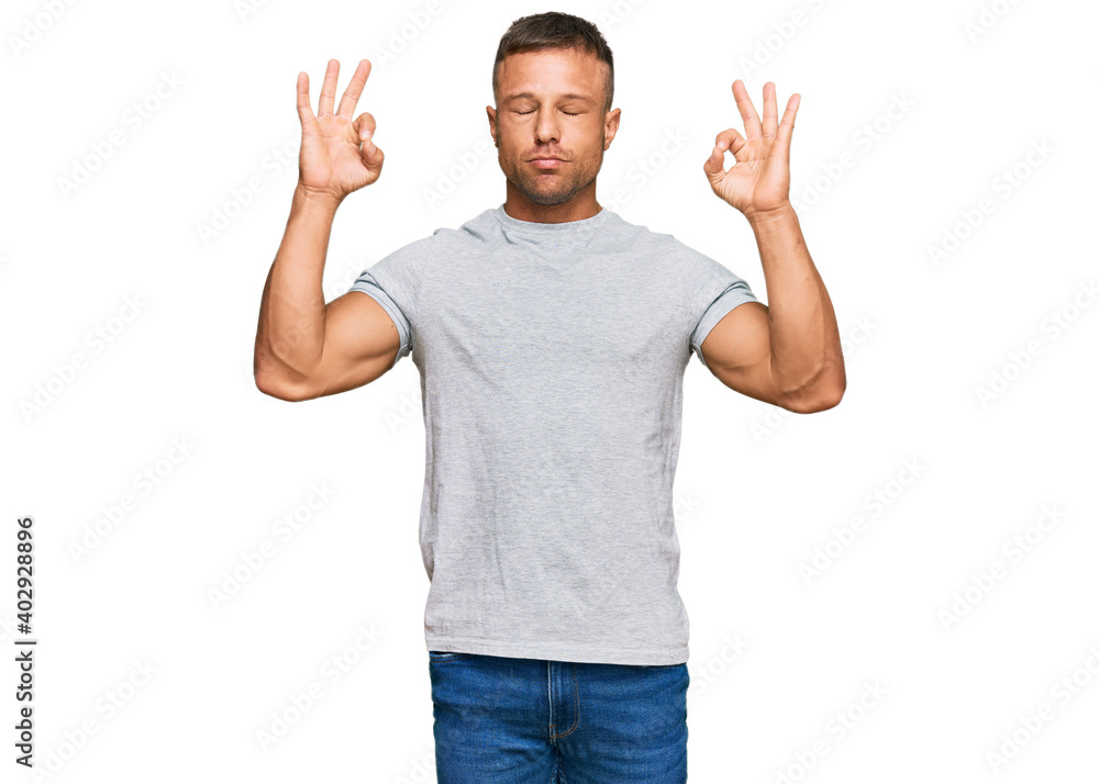 Handsome muscle man wearing casual grey tshirt relax and smiling with eyes closed doing meditation gesture with fingers. yoga concept. Handsome muscle man wearing casual grey tshirt relax and smiling with eyes closed doing meditation gesture with fingers. yoga concept.