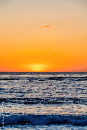 Dark ocean and orange sky at the horizon during sunset at San Diego California