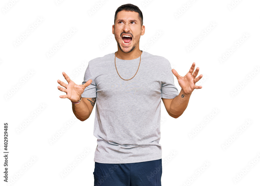 Handsome man with tattoos wearing 90s style crazy and mad shouting and yelling with aggressive expression and arms raised. frustration concept. Handsome man with tattoos wearing 90s style crazy and mad shouting and yelling with aggressive expression and arms raised. frustration concept.