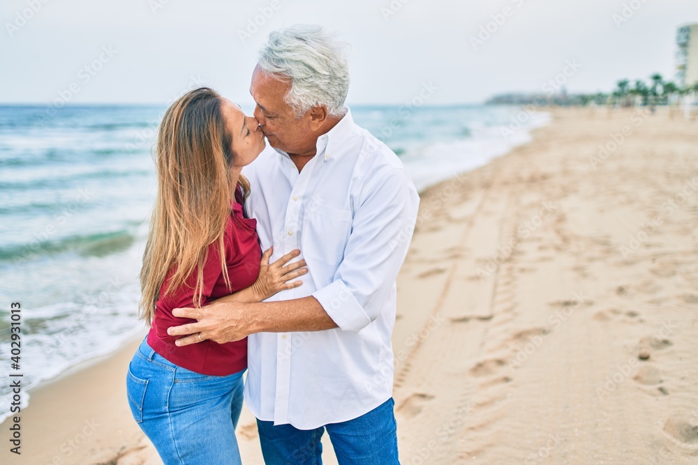 Middle age hispanic couple smiling happy and hugging walking at the beach Middle age hispanic couple smiling happy and hugging walking at the beach