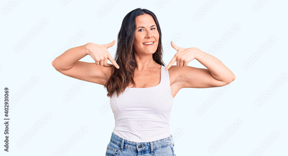 Young beautiful brunette woman wearing casual sleeveless t-shirt looking confident with smile on face, pointing oneself with fingers proud and happy. Young beautiful brunette woman wearing casual sleeveless t-shirt looking confident with smile on face, pointing oneself with fingers proud and happy.