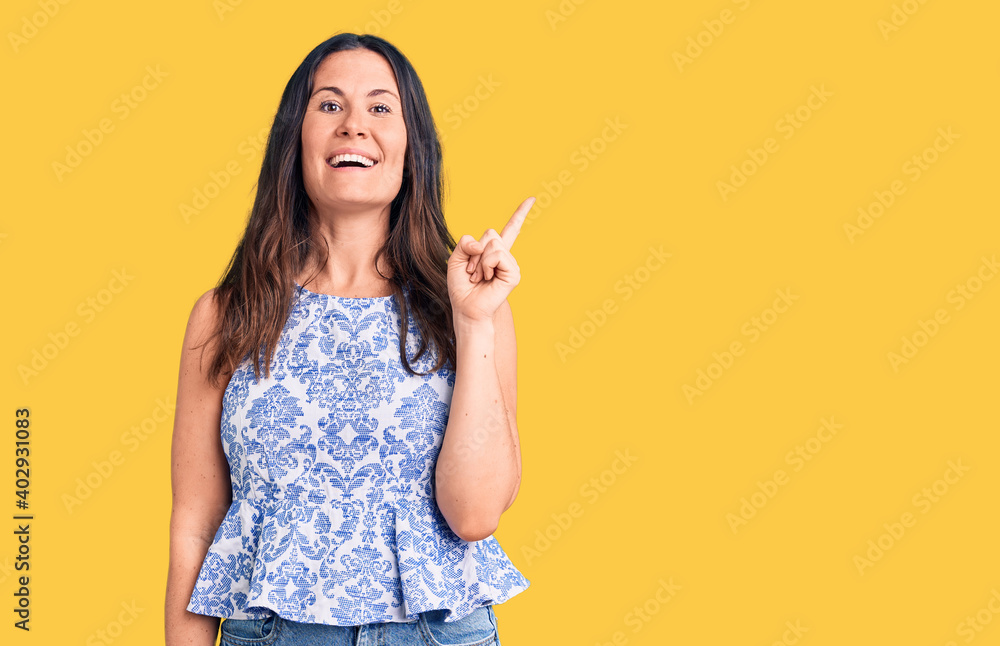 Young beautiful brunette woman wearing casual t-shirt with a big smile on face, pointing with hand and finger to the side looking at the camera. Young beautiful brunette woman wearing casual t-shirt with a big smile on face, pointing with hand and finger to the side looking at the camera.