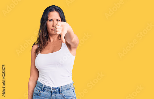 Young beautiful brunette woman wearing casual sleeveless t-shirt looking unhappy and angry showing rejection and negative with thumbs down gesture. bad expression. © Krakenimages.com