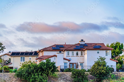 House with solar panels on red tile roof over white wall in San Diego California