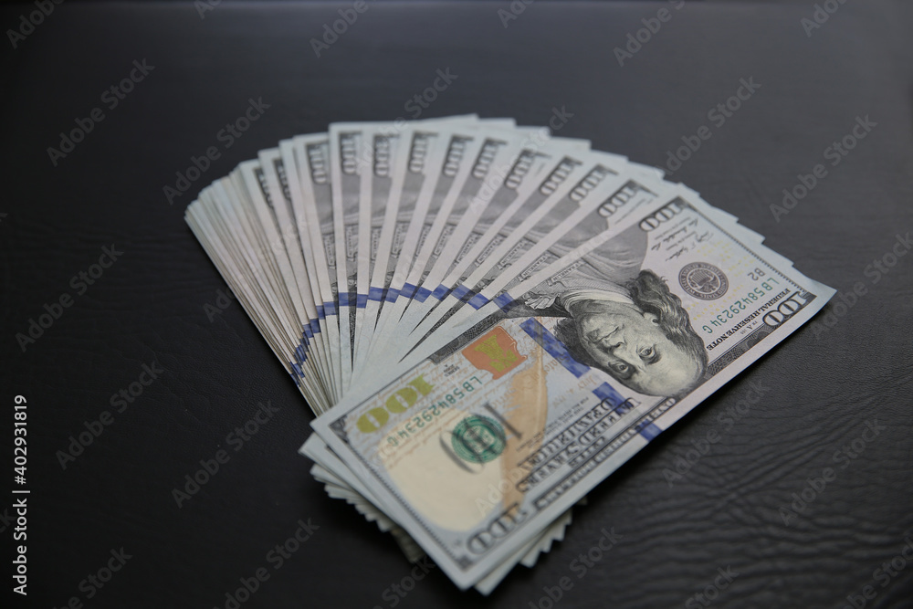 Set of 100 US dollar bills on black leather background. Many american banknotes