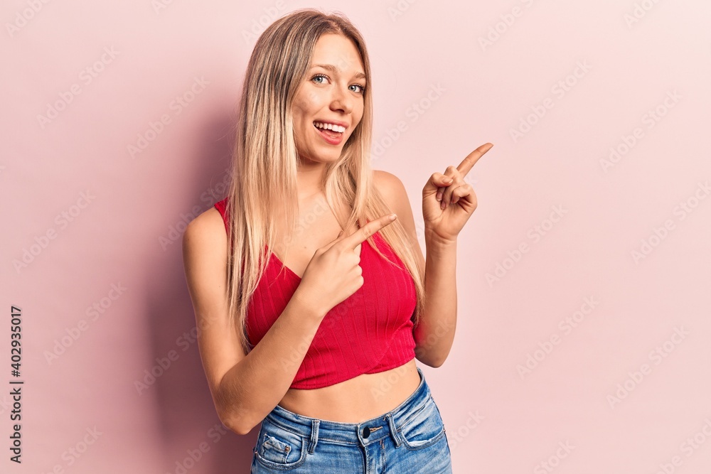 Young blonde woman wearing casual clothes smiling and looking at the camera pointing with two hands and fingers to the side. Young blonde woman wearing casual clothes smiling and looking at the camera pointing with two hands and fingers to the side.