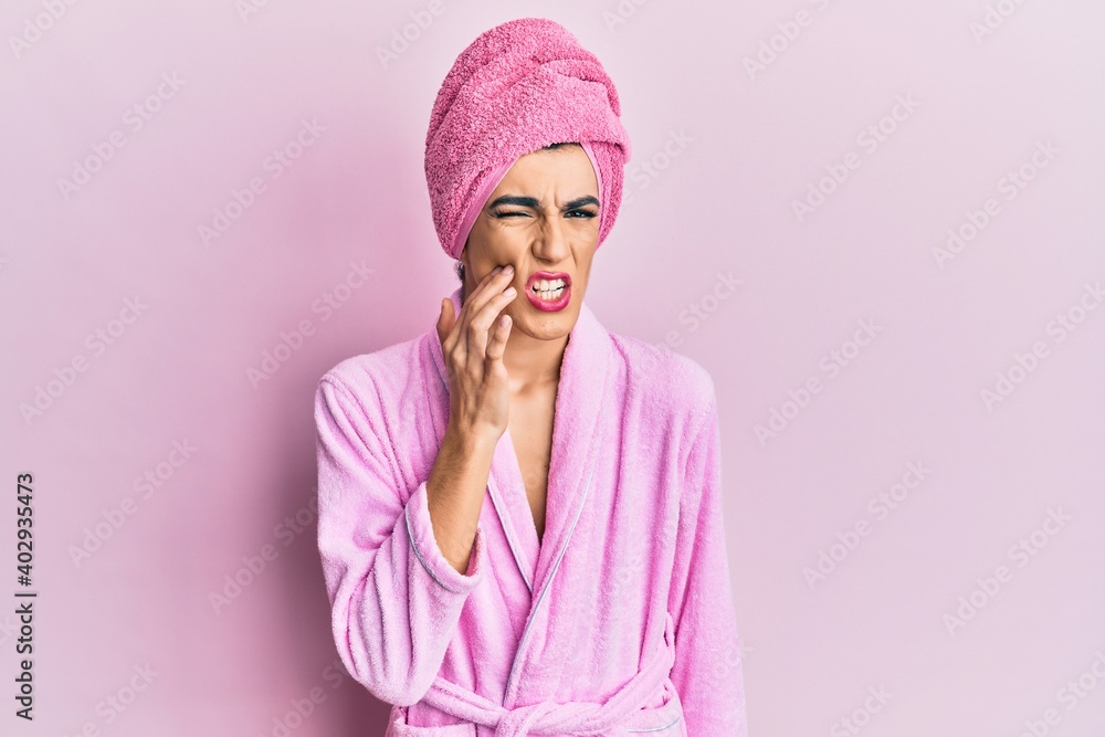 Young man wearing woman make up wearing shower towel on head and bathrobe touching mouth with hand with painful expression because of toothache or dental illness on teeth. dentist Young man wearing woman make up wearing shower towel on head and bathrobe touching mouth with hand with painful expression because of toothache or dental illness on teeth. dentist