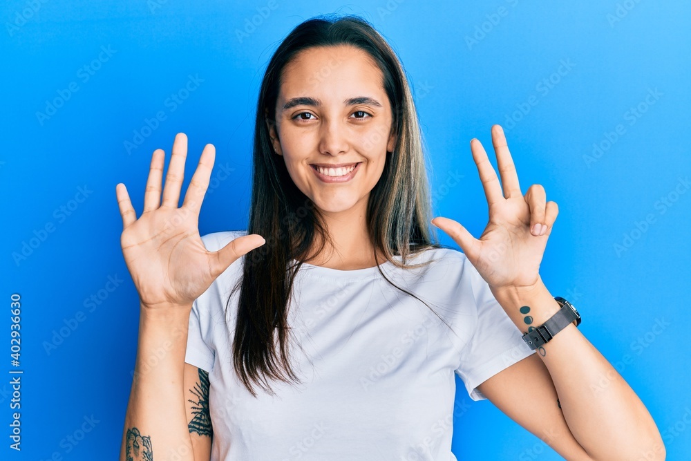 Young hispanic woman wearing casual white t shirt showing and pointing up with fingers number eight while smiling confident and happy. Young hispanic woman wearing casual white t shirt showing and pointing up with fingers number eight while smiling confident and happy.