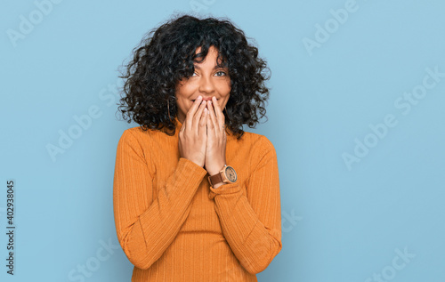 Young hispanic woman wearing casual clothes laughing and embarrassed giggle covering mouth with hands  gossip and scandal concept
