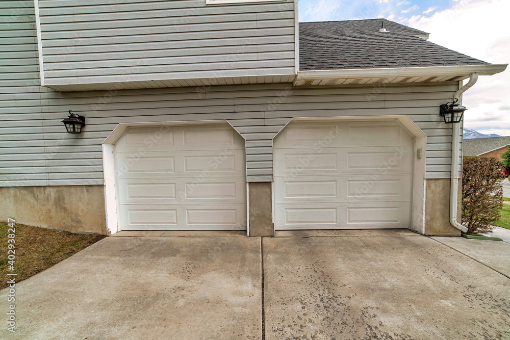 Two car attached garage of house with paved driveway and white panelled doors Two car attached garage of house with paved driveway and white panelled doors