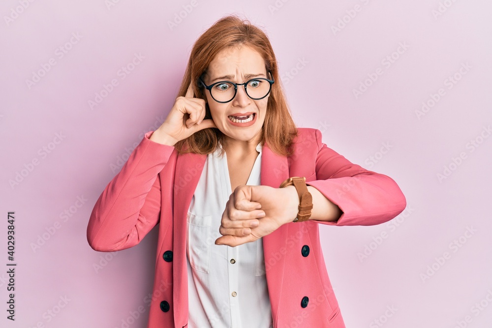 Young caucasian woman wearing business style and glasses looking at the watch time worried, afraid of getting late