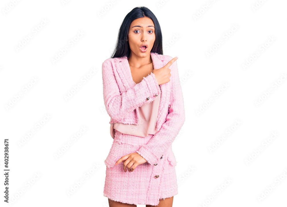 Young beautiful latin girl wearing business clothes surprised pointing with finger to the side, open mouth amazed expression. Young beautiful latin girl wearing business clothes surprised pointing with finger to the side, open mouth amazed expression.