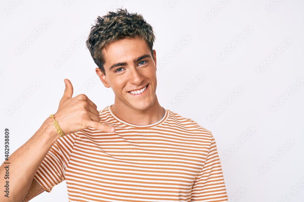 Young handsome man wearing casual clothes smiling doing phone gesture with hand and fingers like talking on the telephone. communicating concepts. Young handsome man wearing casual clothes smiling doing phone gesture with hand and fingers like talking on the telephone. communicating concepts.