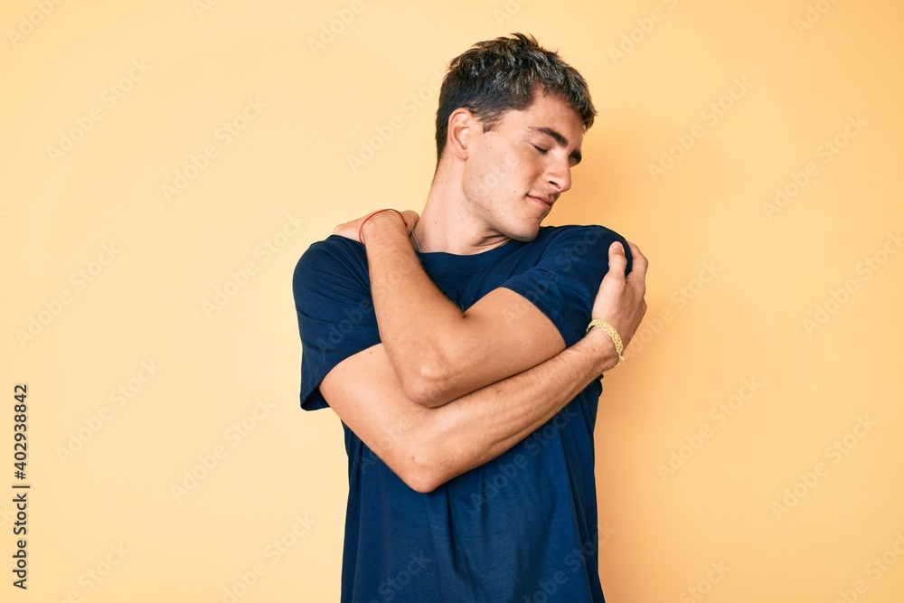 Young handsome man wearing volunteer t shirt hugging oneself happy and positive, smiling confident. self love and self care Young handsome man wearing volunteer t shirt hugging oneself happy and positive, smiling confident. self love and self care