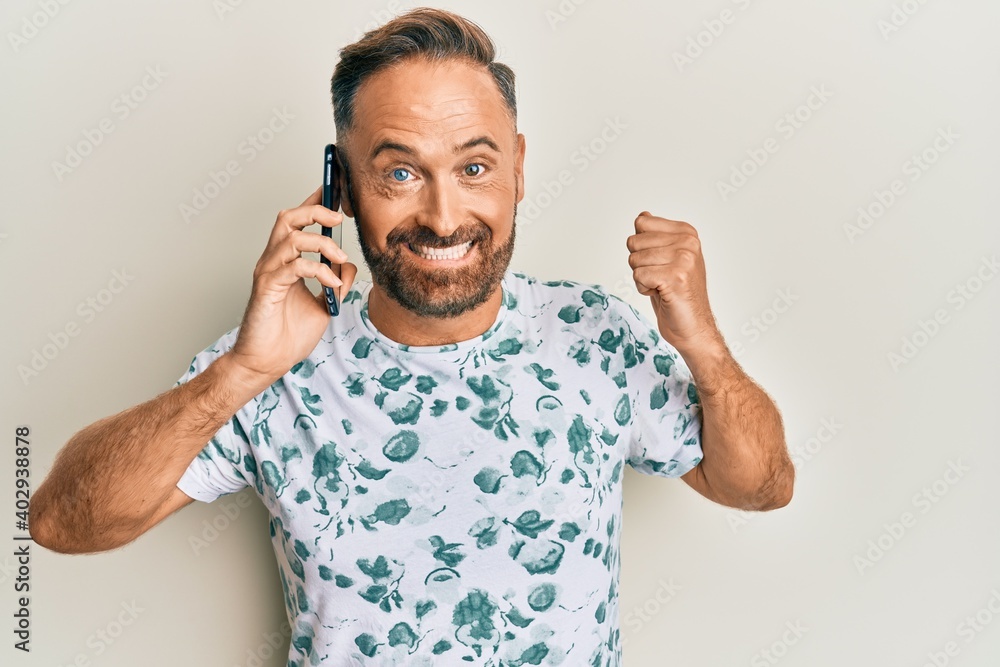 Handsome middle age man having conversation talking on the smartphone screaming proud, celebrating victory and success very excited with raised arm Handsome middle age man having conversation talking on the smartphone screaming proud, celebrating victory and success very excited with raised arm