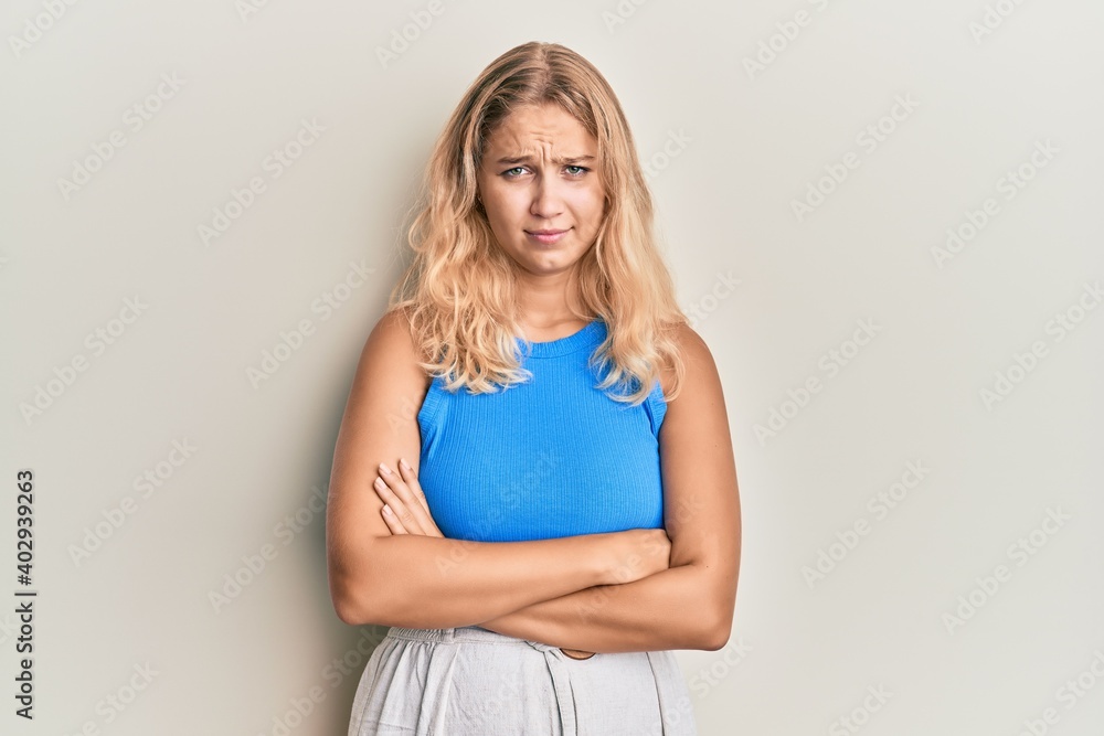 Young blonde girl wearing casual clothes skeptic and nervous, disapproving expression on face with crossed arms. negative person. Young blonde girl wearing casual clothes skeptic and nervous, disapproving expression on face with crossed arms. negative person.
