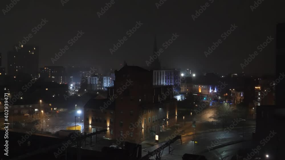 New Year's night scene of Greater Manchester, Salford city Cathedral steeple in the centre. Few fireworks seen in the distance and some flashing behind the building on the right. It is snowing too. New Year's night scene of Greater Manchester, Salford city Cathedral steeple in the centre. Few fireworks seen in the distance and some flashing behind the building on the right. It is snowing too.