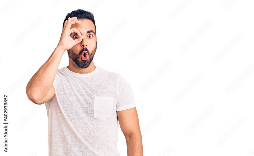 Young hispanic man wearing casual clothes doing ok gesture shocked with surprised face, eye looking through fingers. unbelieving expression. Young hispanic man wearing casual clothes doing ok gesture shocked with surprised face, eye looking through fingers. unbelieving expression.
