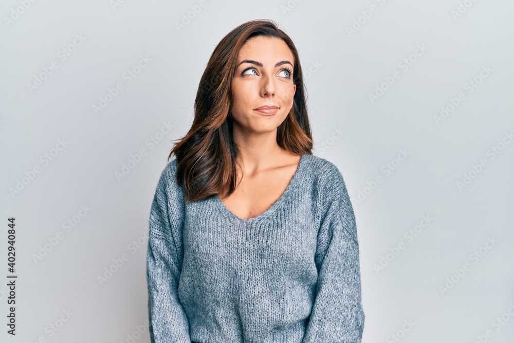Young brunette woman wearing casual winter sweater smiling looking to the side and staring away thinking. Young brunette woman wearing casual winter sweater smiling looking to the side and staring away thinking.