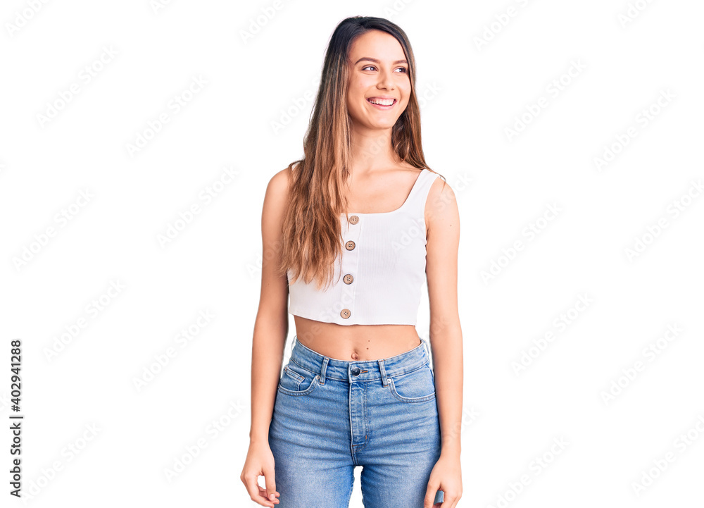 Young beautiful girl wearing casual sleeveless t shirt looking away to side with smile on face, natural expression. laughing confident. Young beautiful girl wearing casual sleeveless t shirt looking away to side with smile on face, natural expression. laughing confident.