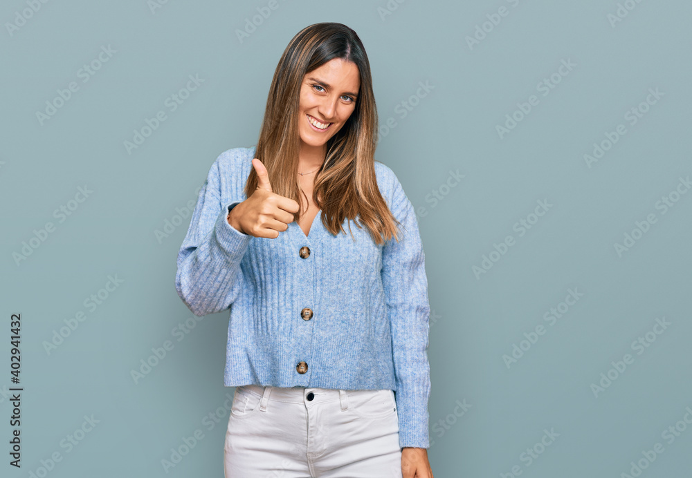 Young woman wearing casual clothes doing happy thumbs up gesture with hand. approving expression looking at the camera showing success. Young woman wearing casual clothes doing happy thumbs up gesture with hand. approving expression looking at the camera showing success.