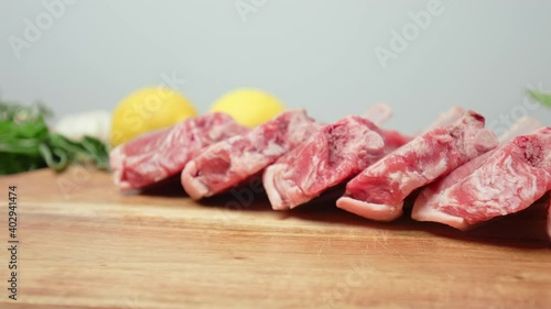 Close-up raw chopped lamb ribs on cutting board with decorative vegetables in 4K. Concept of fresh redraw lamb cutlets sliced from a rack with bones nicely arranged on the table in slow-motion.