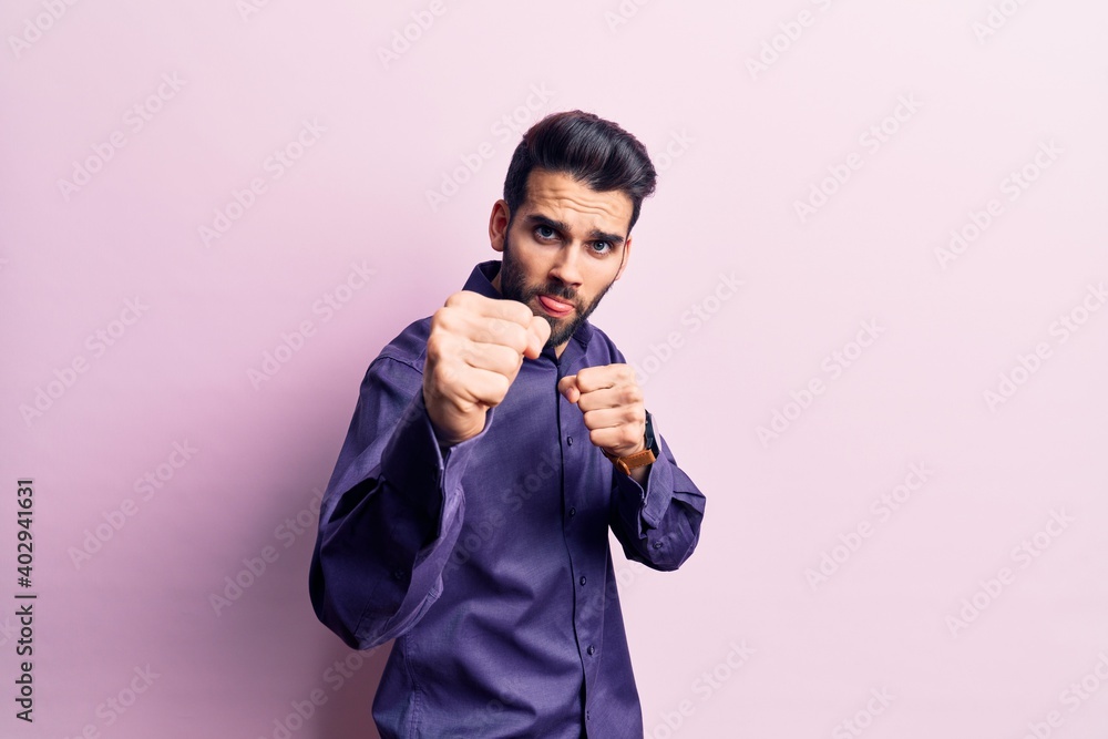 Young handsome man with beard wearing casual shirt punching fist to fight, aggressive and angry attack, threat and violence Young handsome man with beard wearing casual shirt punching fist to fight, aggressive and angry attack, threat and violence