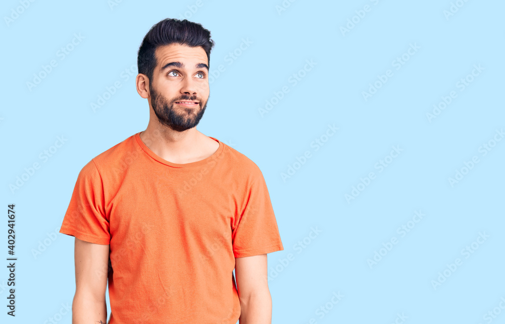 Young handsome man with beard wearing casual t-shirt smiling looking to the side and staring away thinking. Young handsome man with beard wearing casual t-shirt smiling looking to the side and staring away thinking.
