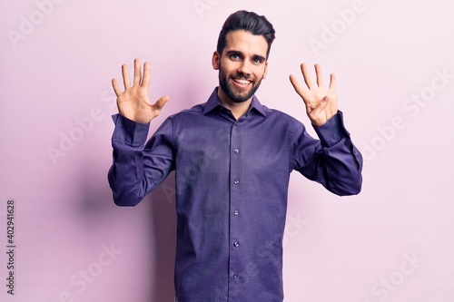 Young handsome man with beard wearing casual shirt showing and pointing up with fingers number nine while smiling confident and happy.