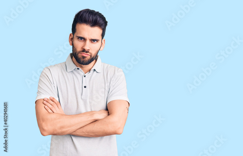 Young handsome man with beard wearing casual polo skeptic and nervous, disapproving expression on face with crossed arms. negative person.