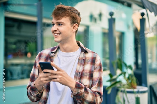 Young caucasian man smiling happy using smartphone at the city.